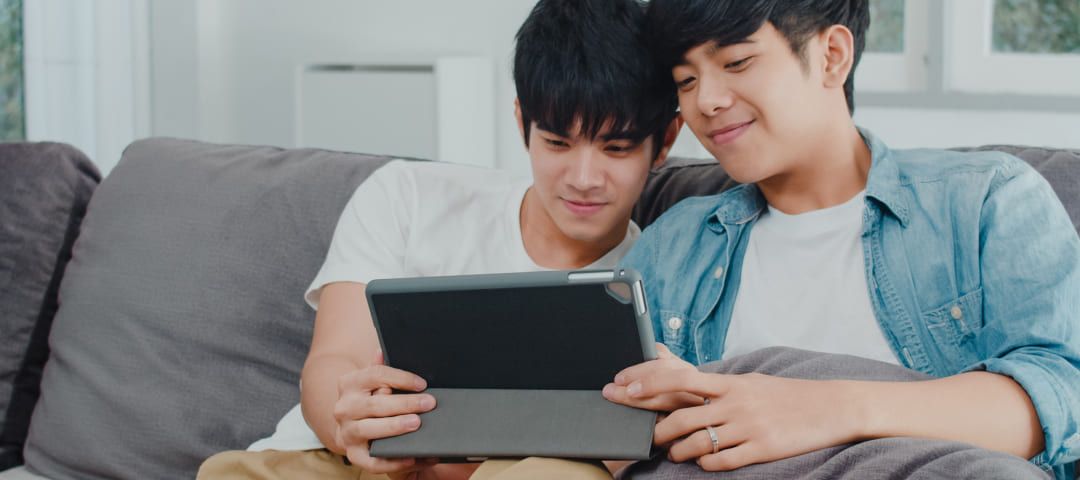 Photo of two men on a couch looking at a tablet