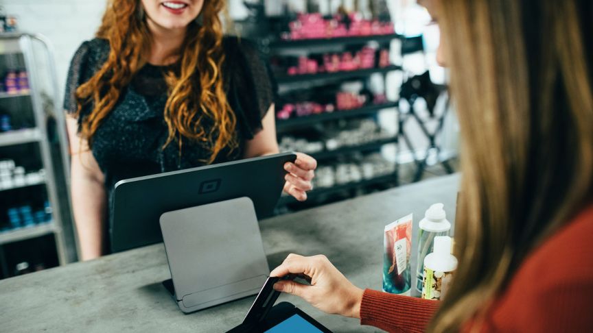 Photo of a woman tapping a card at a retail checkout