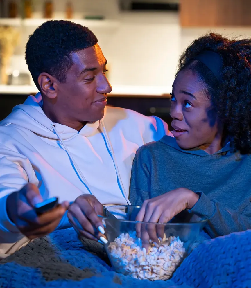 WTC Communications Kingston - Happy couple streaming content at home with popcorn, enjoying WTC's internet and TV services.