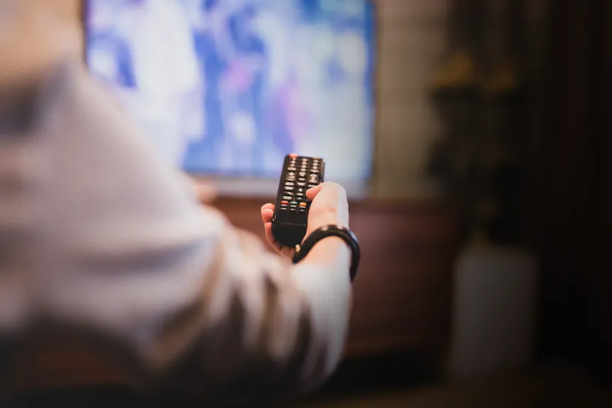 Relaxed person using TV remote watching NHL on WTC TV service channels