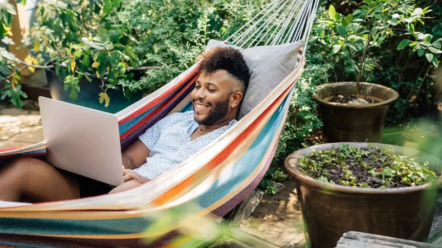Man in hammock with laptop smiling