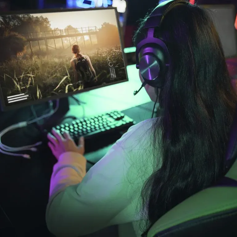 WTC Communications Kingston - Young woman with headset playing an online video game on her PC, highlighting high-speed fibre internet in Kingston.