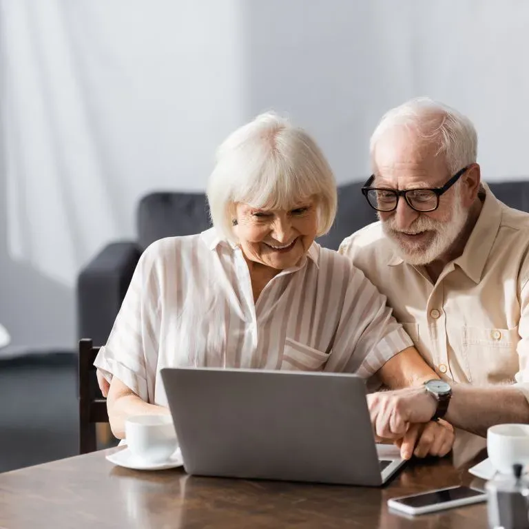 WTC Communications Gananoque - Happy senior couple enjoying fast fibre internet on a laptop at home.
