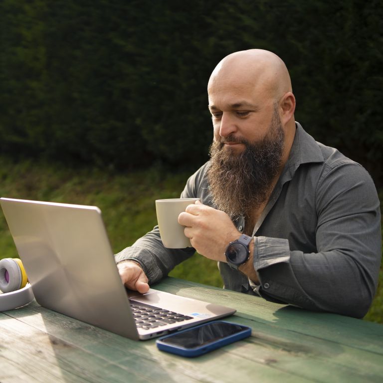 Man with coffee and laptop outside